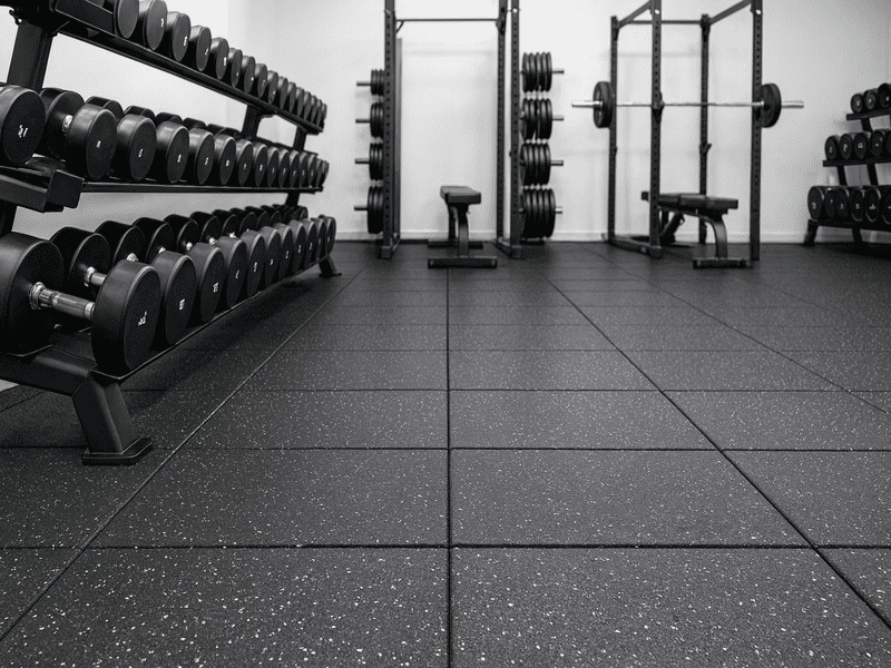 Uma criança brinca em segurança em cima de azulejos de borracha coloridos e interligados numa sala de jogos.